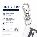 Silver lobster clasp keychain ring accessory shown on a white background with marketing text describing features and a small white key tag partially visible.